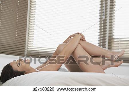 Young woman lying on bed looking up View Large Photo Image Stock Photograph - Young woman lying on bed looking up. Fotosearch