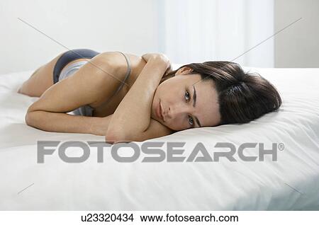 Picture - Young woman lying on bed portrait. Fotosearch