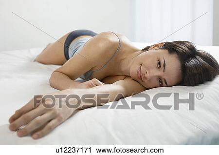 Young woman lying on bed portrait View Large Photo Image Stock Image - Young woman lying on bed portrait. Fotosearch