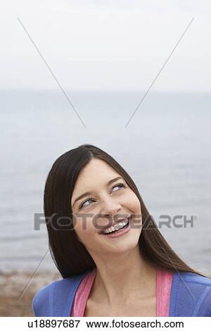 Young woman on beach looking up and smiling View Large Photo Image Stock Photo - Young woman on beach looking up and smiling. Fotosearch