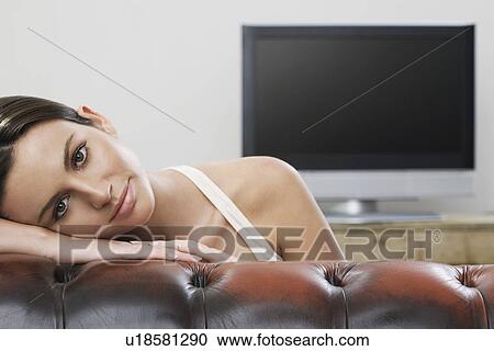 Young woman on sofa in front of flat screen television portrait View Large Photo Image Stock Image - Young woman on sofa in front of flat screen television portrait. Fotosearch