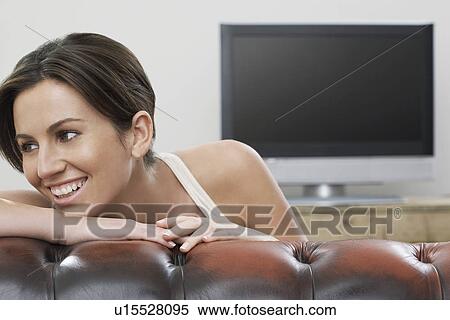 Young woman on sofa in front of flat screen television View Large Photo Image Stock Photography - Young woman on sofa in front of flat screen television. Fotosearch