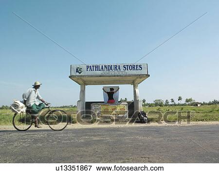 Young woman sitting at bus stop holding map back view man on bicycle passing by View Large Photo Image Stock Photo - Young woman sitting at bus stop holding map back view man on bicycle passing by. Fotosearch