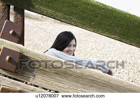 Young woman sitting behind wooden balustrade on beach View Large Photo Image Stock Photo - Young woman sitting behind wooden balustrade on beach. Fotosearch