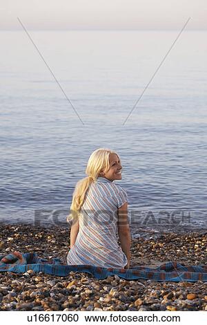 Young woman sitting on beach back view View Large Photo Image Stock Image - Young woman sitting on beach back view. Fotosearch
