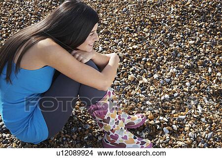 Young woman sitting on beach side view side view View Large Photo Image Picture - Young woman sitting on beach side view side view. Fotosearch