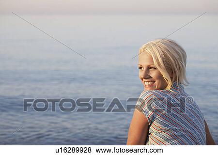 Young woman sitting on beach side view View Large Photo Image Stock Photo - Young woman sitting on beach side view. Fotosearch