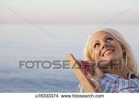 Young woman sitting on deckchair on beach close up portrait View Large Photo Image Picture - Young woman sitting on deckchair on beach close up portrait. Fotosearch