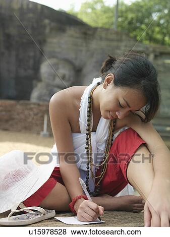 Young woman sitting on ground writing statue of sleeping Buddha in background View Large Photo Image Stock Photo - Young woman sitting on ground writing statue of sleeping Buddha in background. Fotosearch