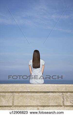 Young woman sitting on stone ledge back view View Large Photo Image Stock Image - Young woman sitting on stone ledge back view. Fotosearch