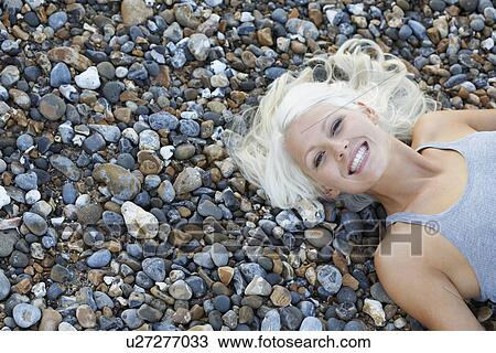 Young woman smiling lying on pebble beach view from above View Large Photo Image Stock Image - Young woman smiling lying on pebble beach view from above. Fotosearch
