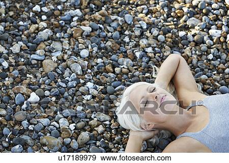 Young woman smiling lying on pebble beach elevated view View Large Photo Image Stock Photo - Young woman smiling lying on pebble beach elevated view. Fotosearch