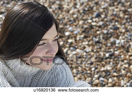 Stock Photograph - Young woman smiling sitting on beach close-up. Fotosearch