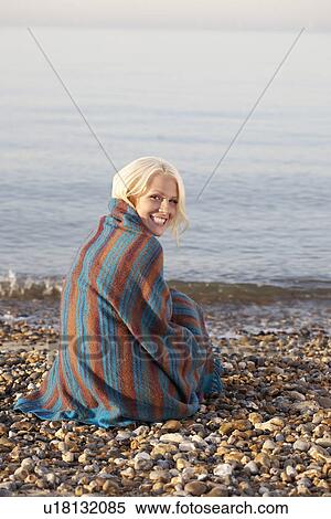 Young woman smiling sitting on beach covered in blanket portrait View Large Photo Image Stock Photography - Young woman smiling sitting on beach covered in blanket portrait. Fotosearch