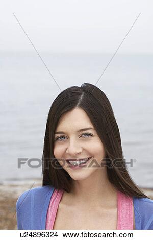 Young woman smiling standing on beach View Large Photo Image Picture - Young woman smiling standing on beach. Fotosearch