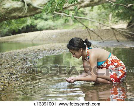 Young woman squatting in lake side view View Large Photo Image Stock Image - Young woman squatting in lake side view. Fotosearch