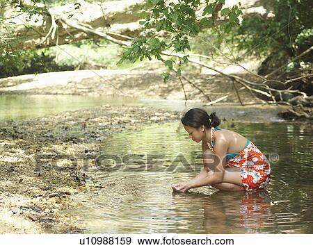 Young woman squatting in lake side view View Large Photo Image Stock Photo - Young woman squatting in lake side view. Fotosearch