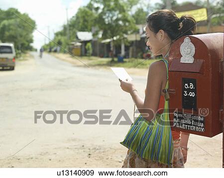 Young woman standing by mailbox reading postcard View Large Photo Image Stock Photo - Young woman standing by mailbox reading postcard. Fotosearch