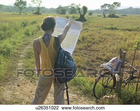 Young woman standing in fields holding map back view View Large Photo Image Stock Image - Young woman standing in fields holding map back view. Fotosearch