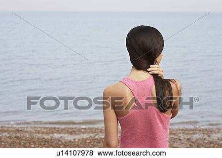 Young woman standing on beach back view View Large Photo Image Stock Photo - Young woman standing on beach back view. Fotosearch
