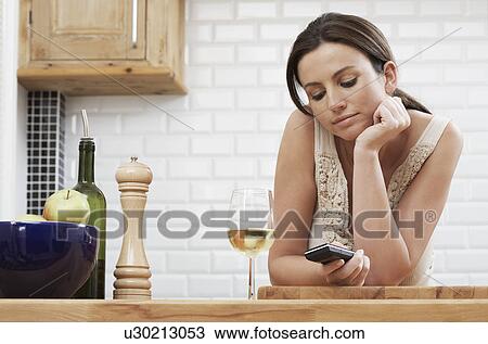 Young woman text messaging leaning on kitchen counter View Large Photo Image Stock Image - Young woman text messaging leaning on kitchen counter. Fotosearch