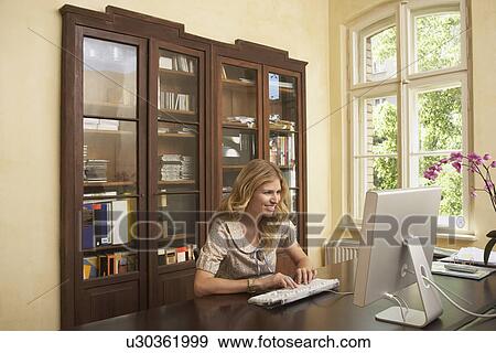 Young woman using computer in living room View Large Photo Image Stock Photo - Young woman using computer in living room. Fotosearch