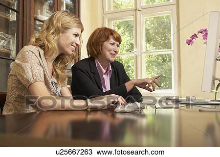 Young woman using computer with middle-aged woman in living room View Large Photo Image Stock Image - Young woman using computer with middle-aged woman in living room. Fotosearch