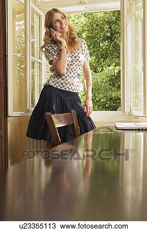 Young woman using mobile phone in living room View Large Photo Image Stock Image - Young woman using mobile phone in living room. Fotosearch