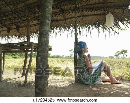 Young woman wearing dress sitting in shade of hut View Large Photo Image Stock Photography - Young woman wearing dress sitting in shade of hut. Fotosearch