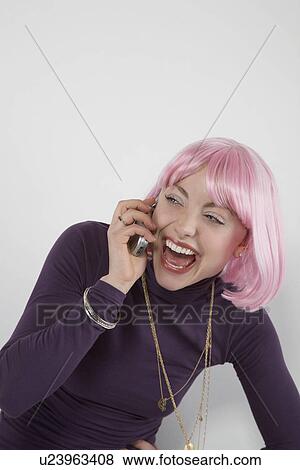 Young woman wearing pink wig laughing into mobile phone View Large Photo Image Stock Photo - Young woman wearing pink wig laughing into mobile phone. Fotosearch