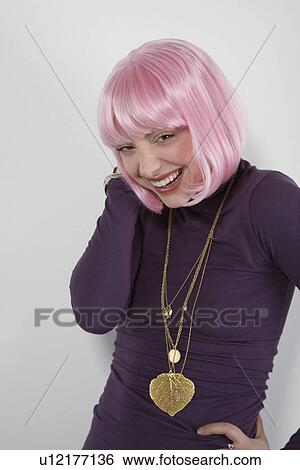 Stock Photograph - Young woman wearing pink wig laughing portrait. Fotosearch