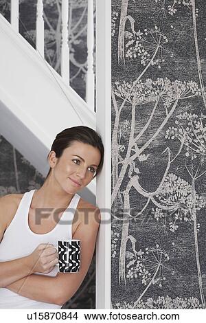 Young woman with cup leaning against staircase View Large Photo Image Picture - Young woman with cup leaning against staircase. Fotosearch