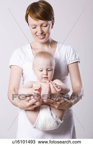 Baby boy (1-2) playing with his feet mother assisting View Large Photo Image Stock Image - Baby boy (1-2) playing with his feet mother assisting. Fotosearch