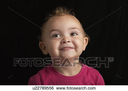 Stock Photograph - Baby girl (1-2) on black background close-up. Fotosearch