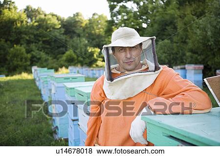 Stock Photo - Beekeeper Standing in Apiary. Fotosearch