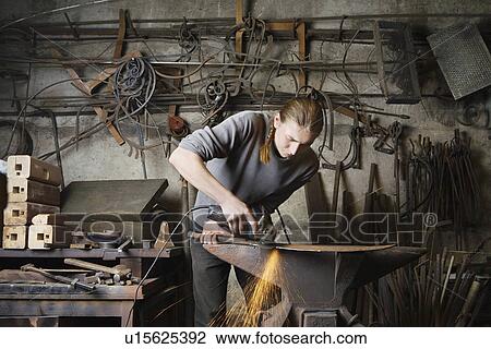 Stock Image - Blacksmith Working in Shop. Fotosearch