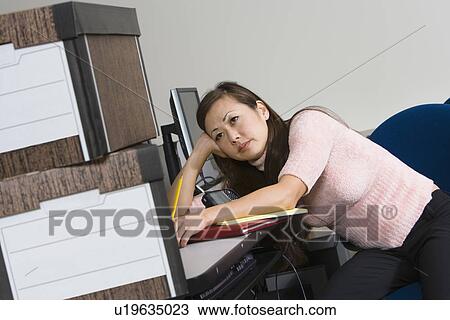 Stock Image - Bored Asian Businesswoman and Moving Boxes. Fotosearch