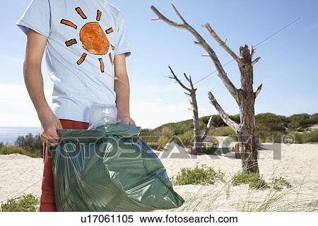 Boy (10-12) holding plastic bag on sand dune mid section View Large Photo Image Stock Photography - Boy (10-12) holding plastic bag on sand dune mid section. Fotosearch