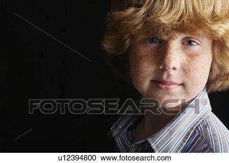Stock Image - Boy (10-12) on black background portrait close-up. Fotosearch