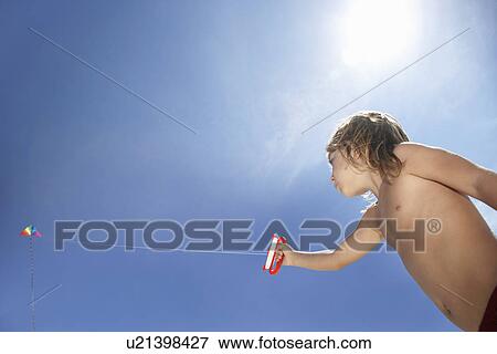 Boy (7-9) flying kite low angle view View Large Photo Image Stock Photo - Boy (7-9) flying kite low angle view. Fotosearch