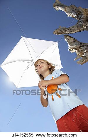Boy (7-9) holding beach umbrella view from below View Large Photo Image Stock Photography - Boy (7-9) holding beach umbrella view from below. Fotosearch