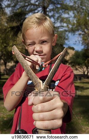 Stock Image - Boy (7-9) using slingshot. Fotosearch