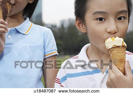 Stock Photo - Boy and girl (7-9) eating ice cream close-up (cropped). Fotosearch