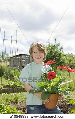 Stock Photo - Boy holding flowers in garden. Fotosearch