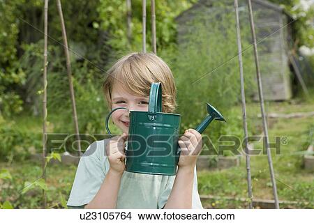 Boy holding watering can in garden View Large Photo Image Picture - Boy holding watering can in garden. Fotosearch