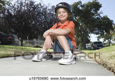 Boy sitting on skateboard View Large Photo Image Stock Image - Boy sitting on skateboard. Fotosearch