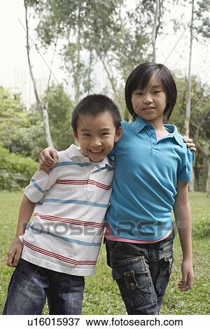 Stock Photo - Brother and sister (7-9) standing in park portrait. Fotosearch