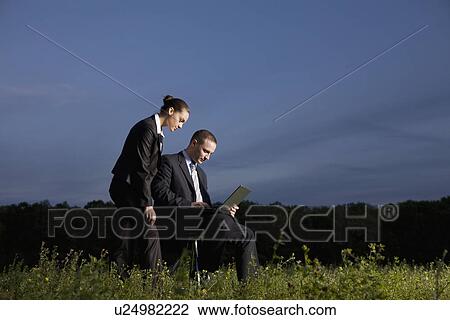 Business couple using laptop in field View Large Photo Image Stock Image - Business couple using laptop in field. Fotosearch