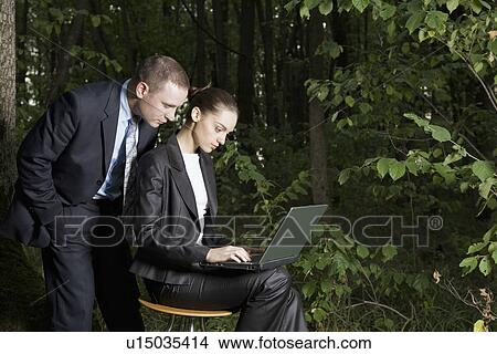 Business couple using laptop in forest View Large Photo Image Picture - Business couple using laptop in forest. Fotosearch