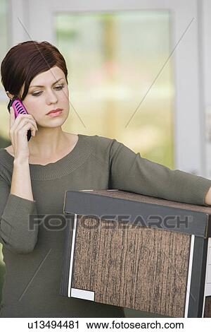 Stock Image - Businesswoman Using Mobile Phone with Moving Box. Fotosearch